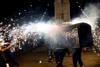 Group of people watching firework display at night