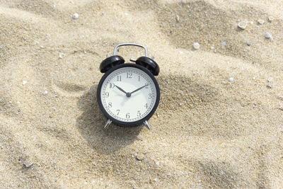 High angle view of clock on sand