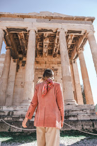 Rear view of woman standing against historical building
