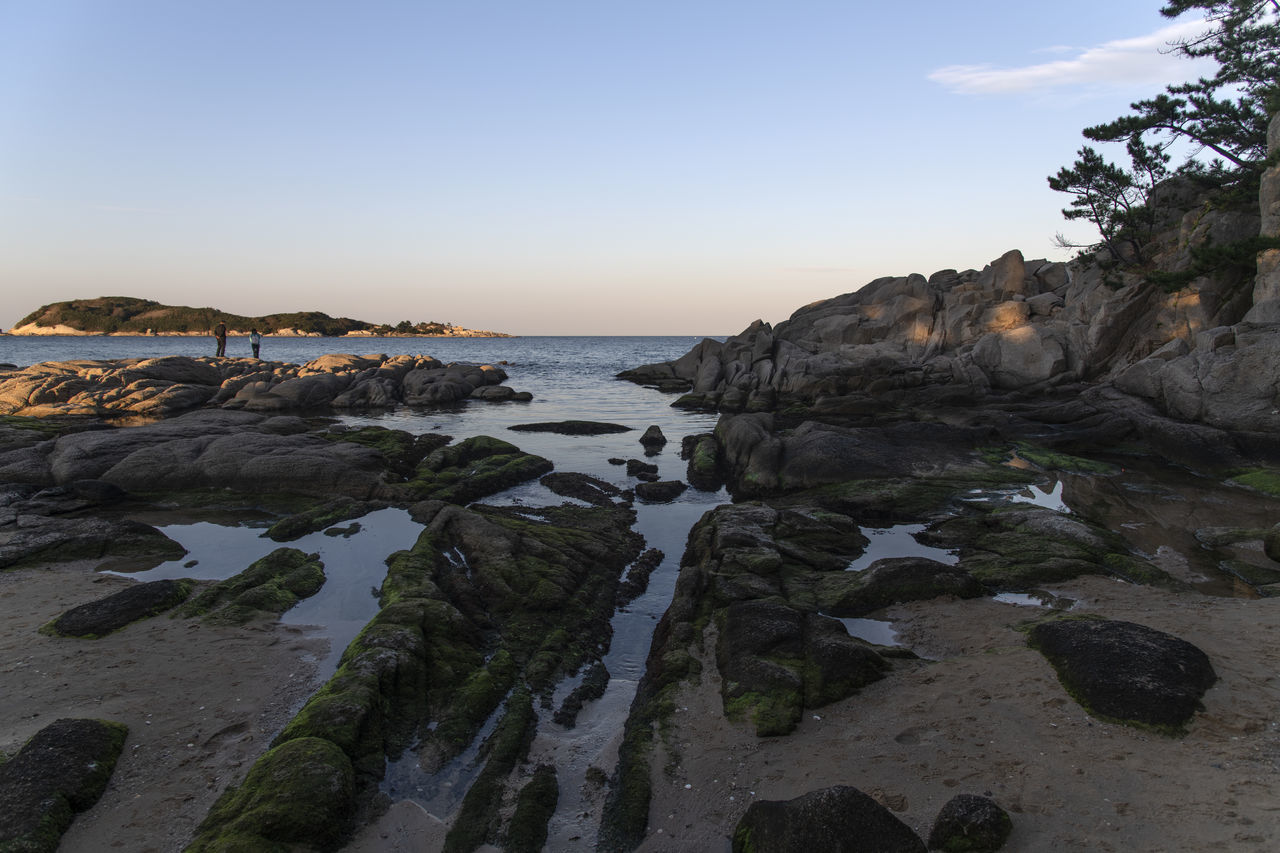 water, sky, rock, sea, land, coast, nature, beach, shore, scenics - nature, beauty in nature, environment, cliff, body of water, landscape, terrain, ocean, travel destinations, travel, clear sky, no people, sunset, coastline, bay, mountain, outdoors, tranquility, tourism, rock formation, non-urban scene, tranquil scene, blue, seascape, trip, holiday, horizon over water, cloud, cove, vacation