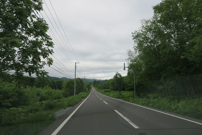 Road amidst trees against sky