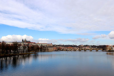 Buildings by river against sky in town