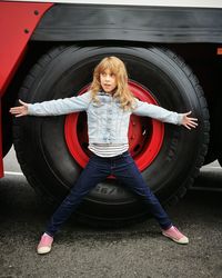 Full length of girl standing against tire