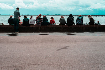 People looking at sea against sky