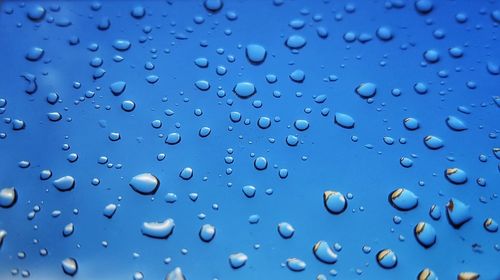 Full frame shot of raindrops on blue window