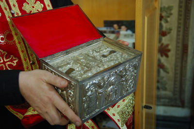 Cropped image of priest holding metal box