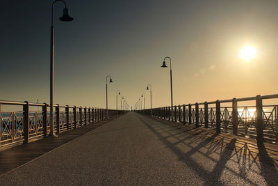 Street light by sea against sky during sunset