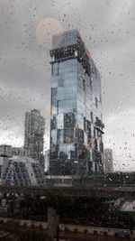 Buildings seen through wet glass window during rainy season