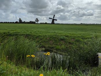 Scenic view of grassy field against cloudy sky