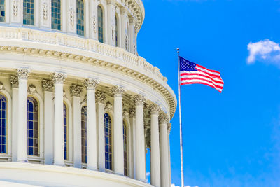 Low angle view of government building and american flag against blue sky