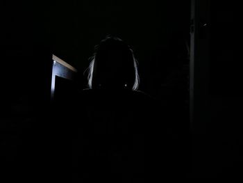 Silhouette of woman standing in darkroom