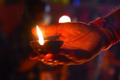 Close-up of hand holding burning candle