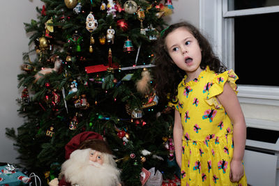 Young girl posing next to a christmas tree and presents