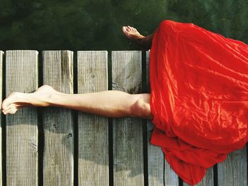 Low section of woman lying on pier over lake