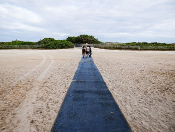 Rear view of people walking on road against sky