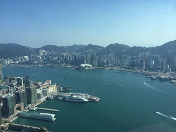 Aerial view of victoria harbor amidst cityscape against clear sky