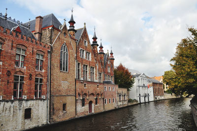 Buildings by river in town against sky