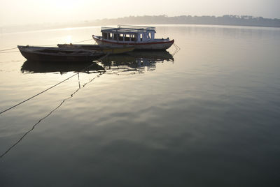 Boat moored in sea against sky during sunset