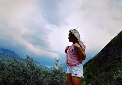 Young woman standing against sky