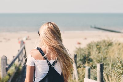 Woman standing at sea shore against sky
