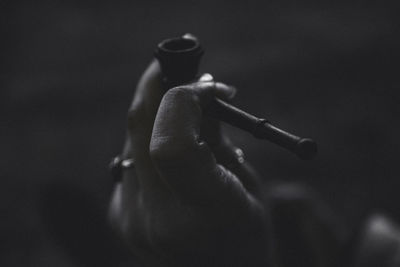 Close-up of hand holding smoking pipe