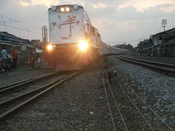 Train on railroad tracks against sky during sunset