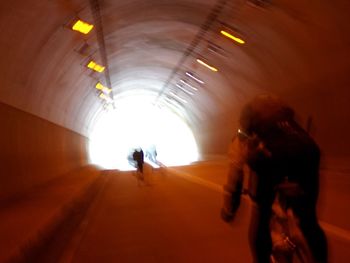 Rear view of people walking in illuminated tunnel