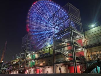 Low angle view of illuminated ferris wheel in city at night