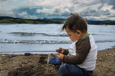 Side view of boy on beach against sky