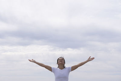 Full length of woman with arms raised against sky