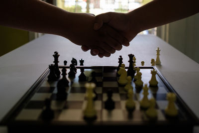 Cropped image of people shaking hands over chess board