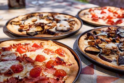 Homemade italian pizza with tomato, cheese and ham in the plate on tile table in the garden. 