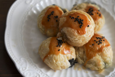 There are some delicious black sesame egg yolk pastries freshly baked on the plate on the table