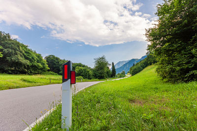 Empty road amidst field against sky