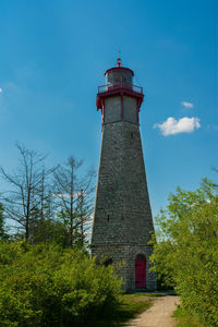 Low angle view of lighthouse by building against sky