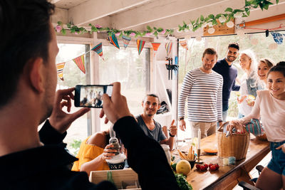 Man photographing friends on smart phone in cottage