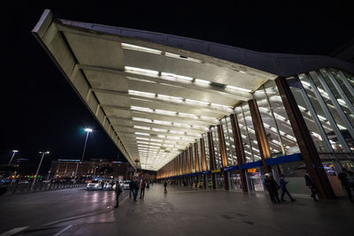 People walking on illuminated bridge at night