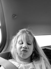 Low angle view of girl puckering lips while sitting in car
