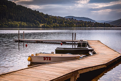 Boat moored by lake against sky