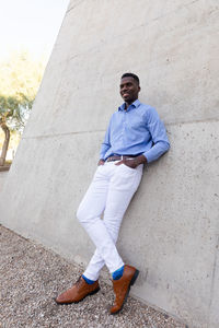 Full size handsome stylish african american man wearing white jeans and blue shirt, brown belt