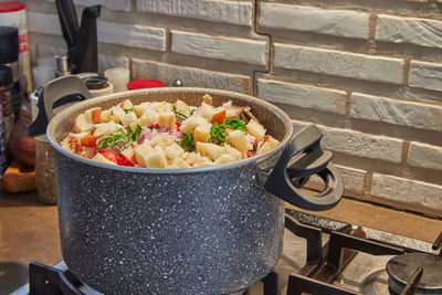 Saucepan on the gas stove with vegetables for soup and pieces of baguette