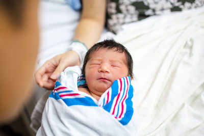 A cute newborn girl wrapped in a blanket is held between her parents