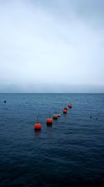 Scenic view of lake with buoys against sky