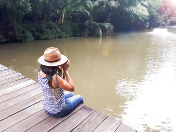 Woman sitting on chair by lake