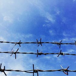 Low angle view of barbed wire against cloudy sky