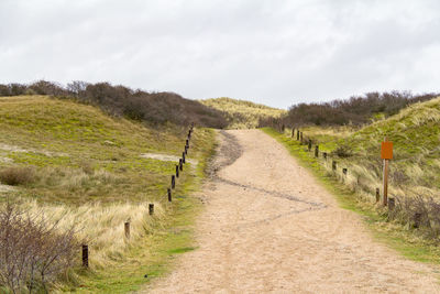 Road amidst field against sky