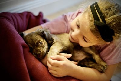 Young girl admiring and embracing a cute puppy.