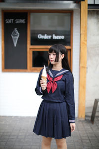 Young woman holding ice cream while standing outdoors