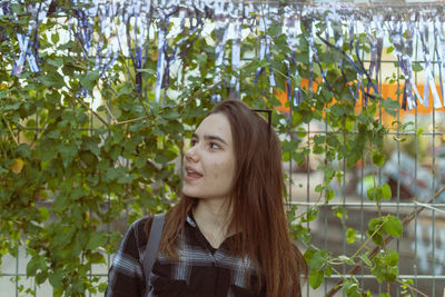 Young woman looking away against plants