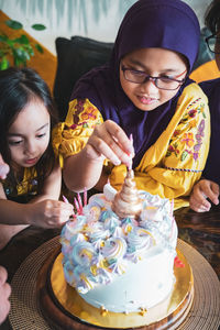 High angle view of siblings decorating birthday cake